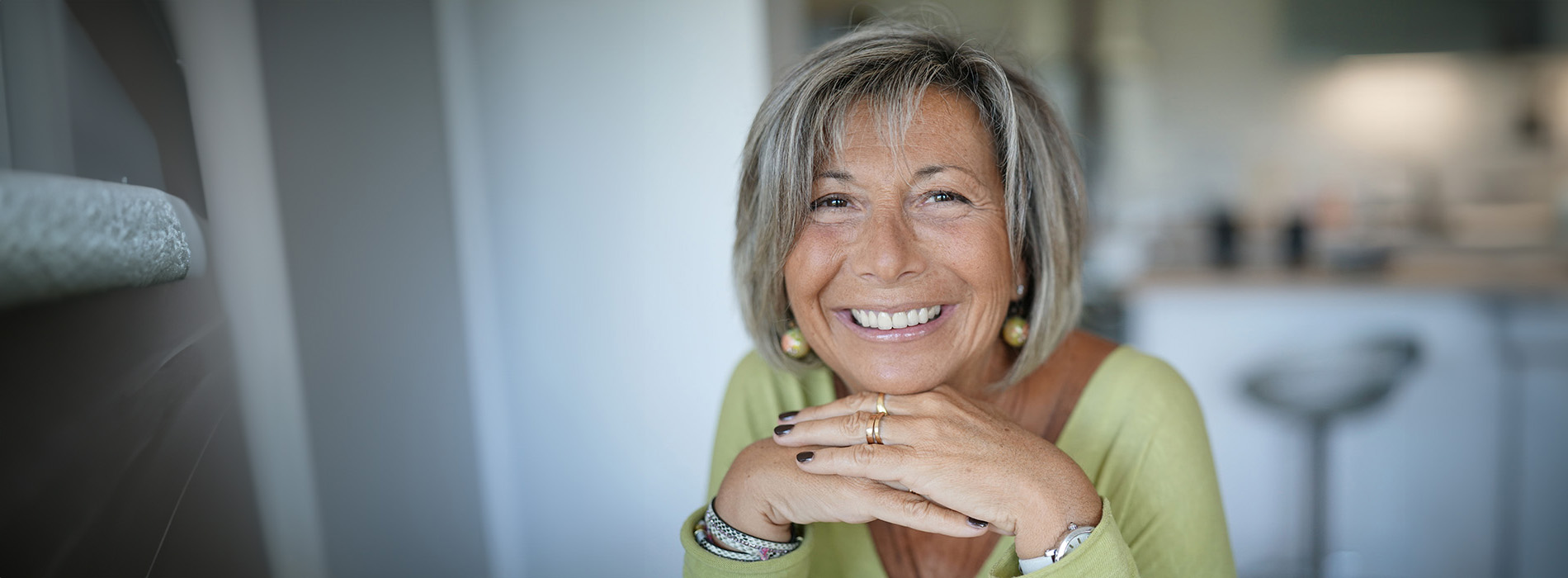 The image is a photograph of a woman with light skin, smiling at the camera. She appears to be in her late twenties or early thirties and has long hair. Her eyes are looking directly at the camera, and she is holding up her index finger near her mouth as if she s making a point or emphasizing something. The background is plain and light-colored, which suggests that this could be a stock photo used for various purposes such as advertising, personal branding, or lifestyle content.