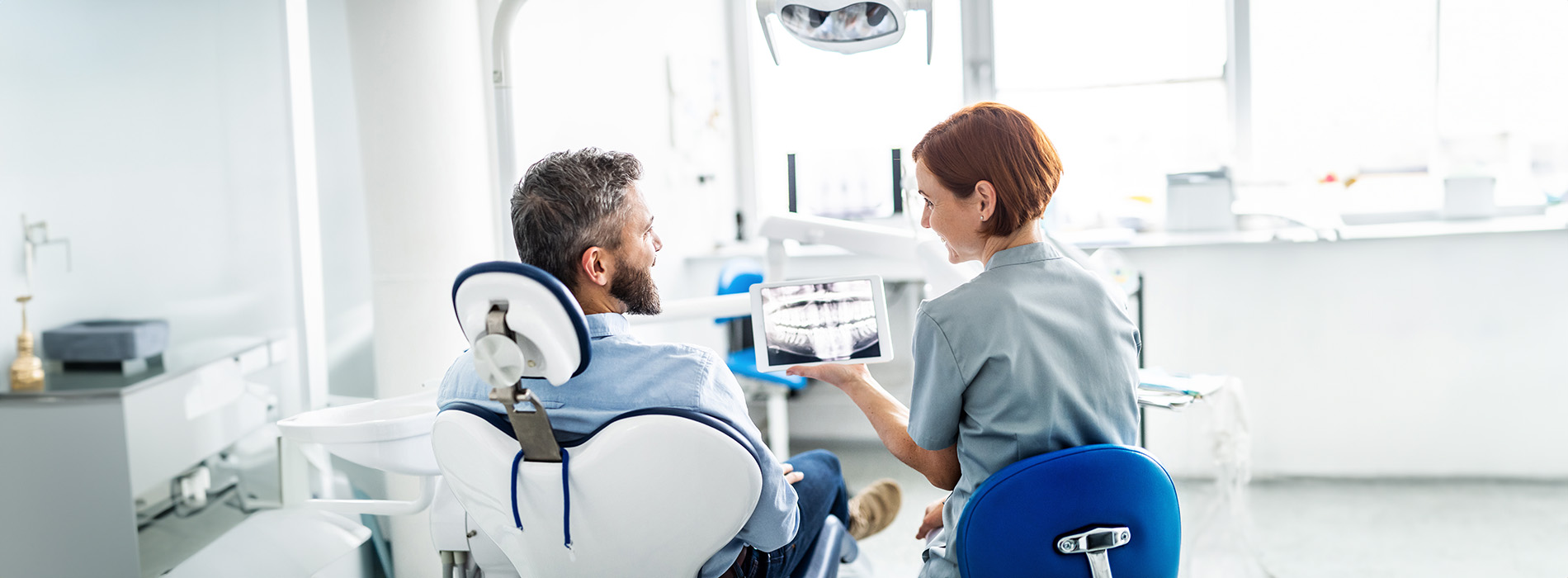 The image shows a modern dental clinic interior with various pieces of equipment, including a dental chair and an X-ray machine.